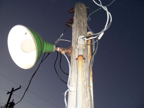 2004 Aston Martin Virage - A green street lamp is mounted on a weathered wooden utility pole against a dark sky.