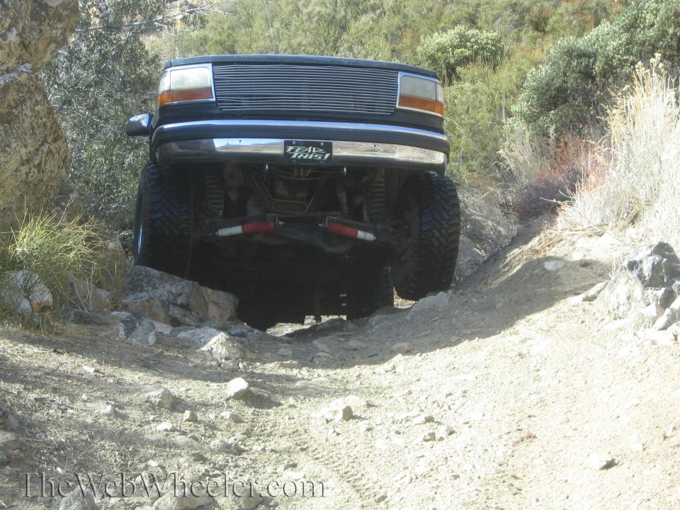 Ford F-150 truck with lifted suspension driving over rocks