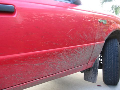 1974 Ford F-100 - Mud covers the side of a red pickup truck, obscuring its model year.