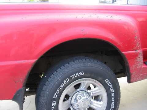 1974 Ford F-100 - The rear fender and tire of a red pickup truck are shown in this close-up view.