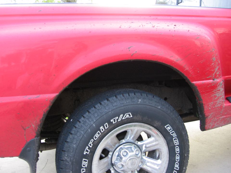 Close-up of a red pickup truck's rear wheel well and tire