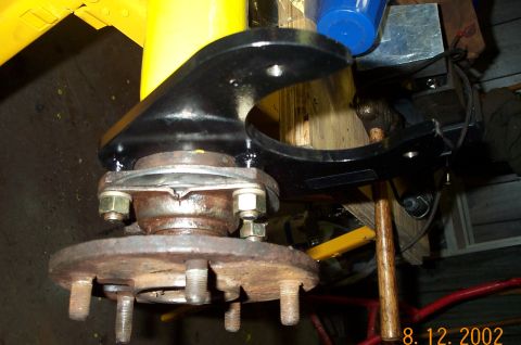1986 Ford Bronco - Close-up view of a vehicle's rear axle component, showing a rusty hub and a black mounting bracket.