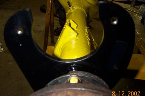 1986 Ford Bronco - A black tool is positioned over a rusty flange on a yellow axle housing.