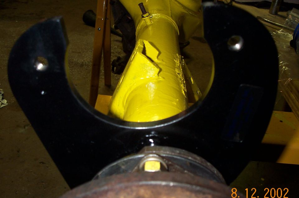 Black U-shaped caliper bracket framing a yellow jack arm, rusty hub flange in foreground