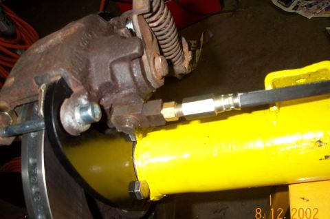 1986 Ford Bronco - Close-up of a vehicle's rear axle brake caliper and brake line assembly.