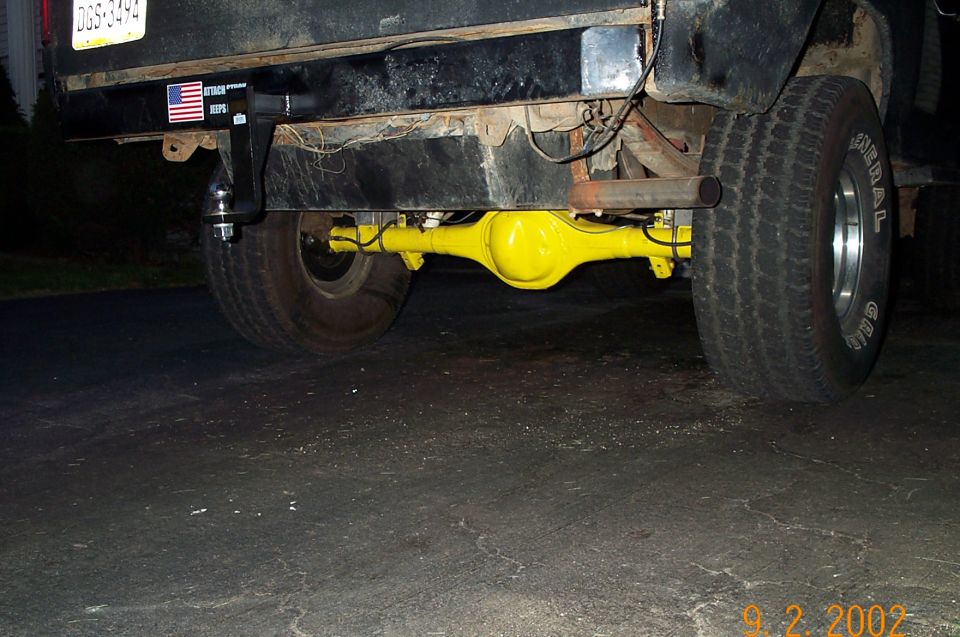 Bright yellow rear axle housing under a black truck with General white-letter tires