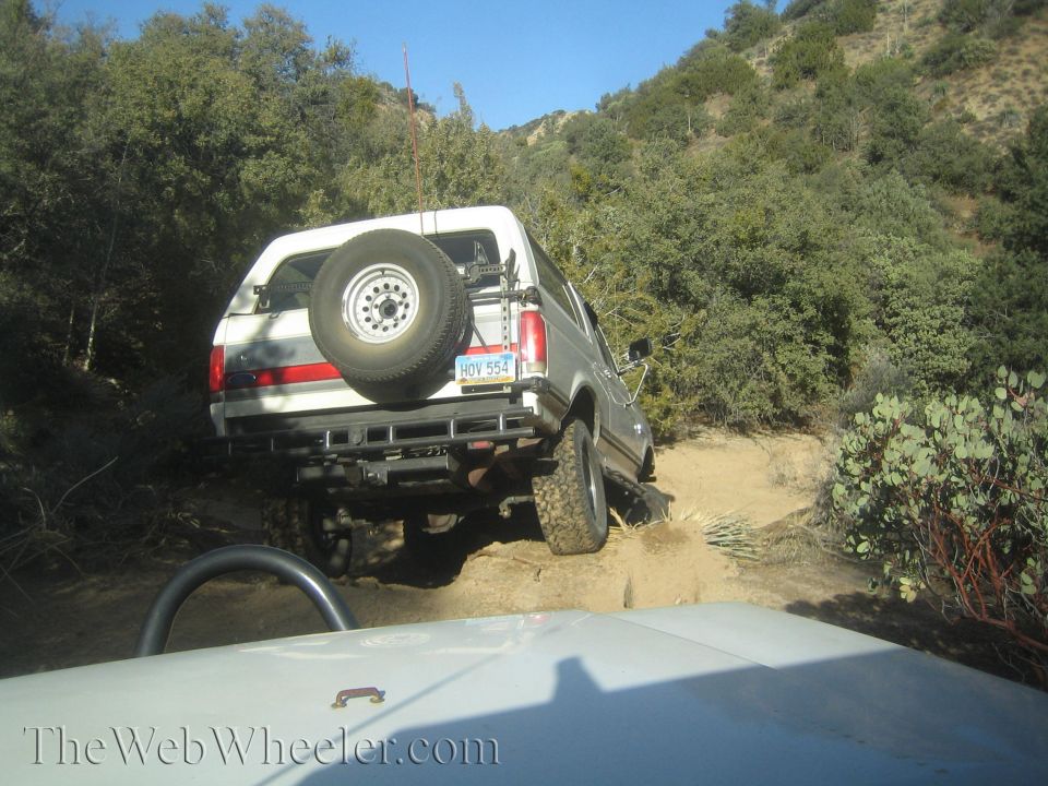 White SUV with spare tire on rear, driving off-road
