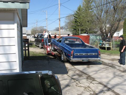 1976 Ford Ranchero - A blue Ford Ranchero is being loaded onto a trailer by two men.