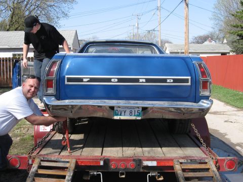 1976 Ford Ranchero - A blue Ford Ranchero is being loaded onto a trailer by two men.