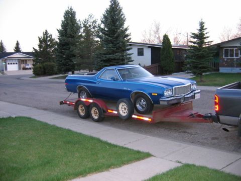1976 Ford Ranchero - A blue coupe utility is loaded onto a trailer, ready for transport.