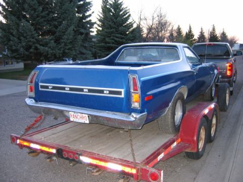 1976 Ford Ranchero - Blue 1976 Ford Ranchero being transported on a trailer, with a pickup truck in front.