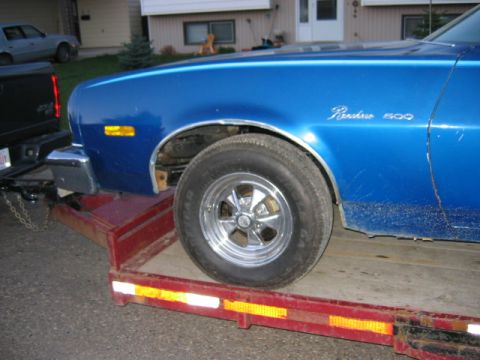 1976 Ford Ranchero - A blue 1976 Ford Ranchero 500 is loaded onto a trailer, with another vehicle visible in the background.