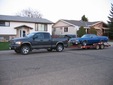 1976 Ford Ranchero - A blue 1976 Ford Ranchero is transported on a trailer behind a pickup truck.