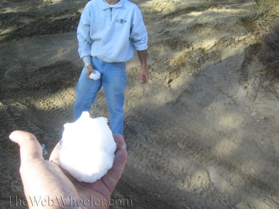 Person in blue jeans and gray sweatshirt holds a snowball
