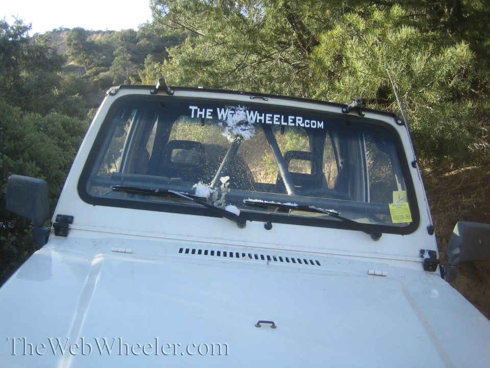 1987 Suzuki Samurai interior view showing roll cage and windshield with 'THE WEB WHEELER.COM' sticker