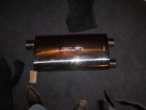 1991 Ford Bronco - A shiny SLP exhaust muffler is shown on a dark carpeted surface.