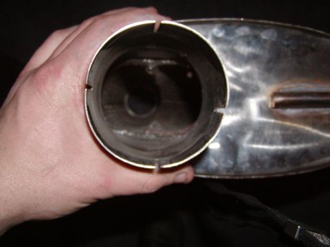 1991 Ford Bronco - A hand holds a chrome exhaust pipe, revealing its internal structure and baffles.