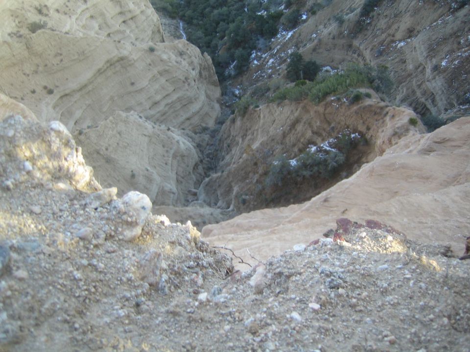 View looking down into a dry, eroded canyon with sparse vegetation on the slopes