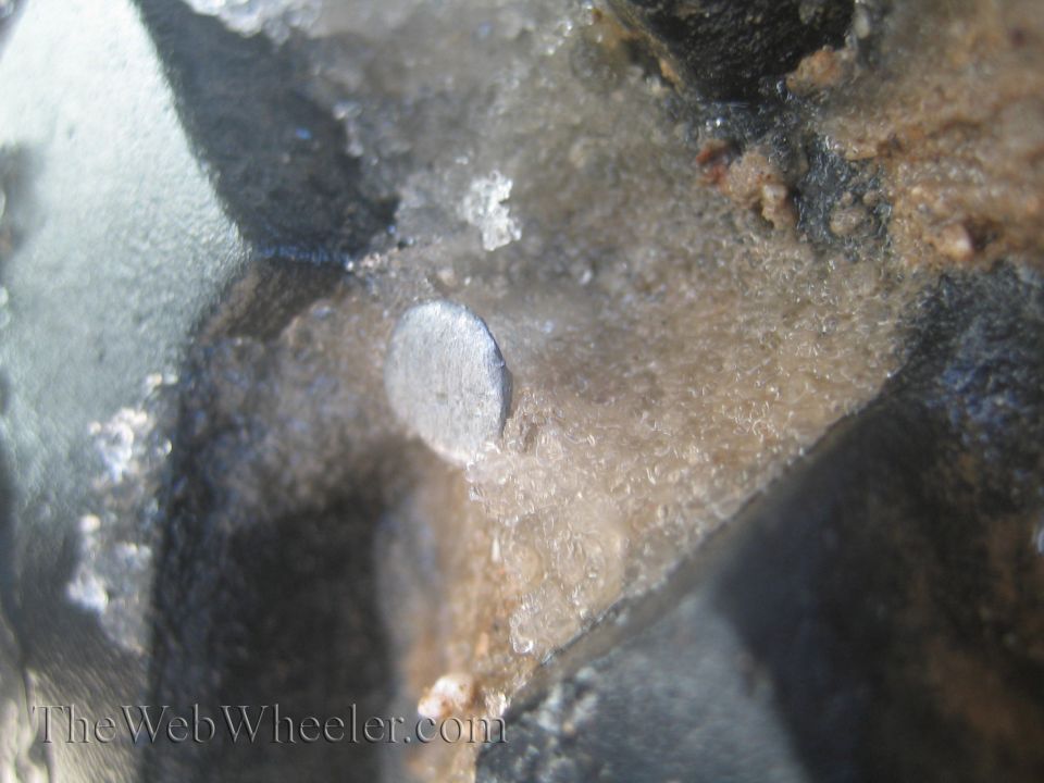 Close-up of a metal pin embedded in ice and dirt