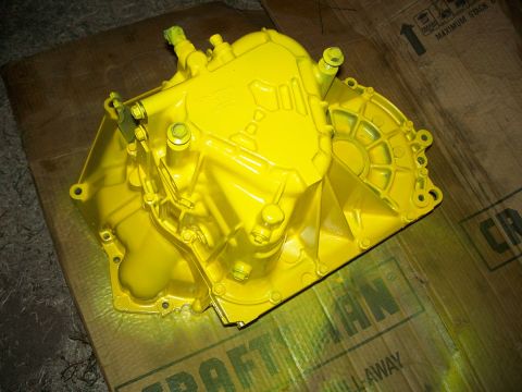 1992 Ford Taurus - A bright yellow transmission part sits on a piece of cardboard, likely awaiting installation or inspection.