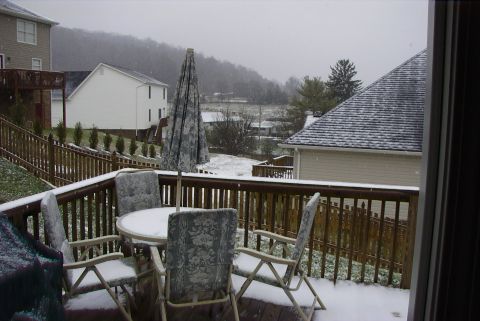 1995 Ford Bronco - Snowy scene from a backyard deck, showing furniture and houses in the distance.