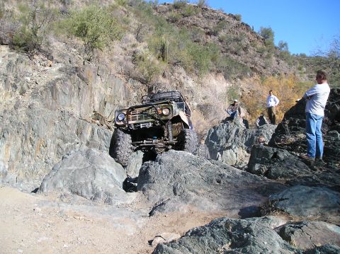 1966 Ford Bronco - Off-road vehicle tackling a challenging rocky path with spectators watching.