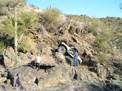1966 Ford Bronco - Off-road vehicle stuck on a steep, rocky incline with two people observing.