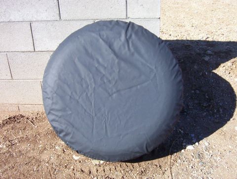 1995 Ford Bronco - Spare tire cover shown next to a cinder block wall outdoors.