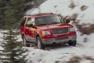 2003 Ford Expedition - A red 2003 Ford Expedition navigates a snowy path with trees in the background.