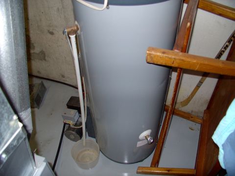 1986 Ford Bronco - A water heater stands in a basement next to a wooden rack holding hockey sticks and a metal pipe.