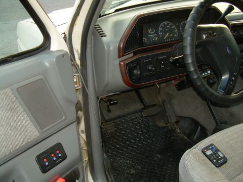1988 Ford Bronco - The interior of a truck shows the dashboard, steering wheel, and door panel with aftermarket switches installed.