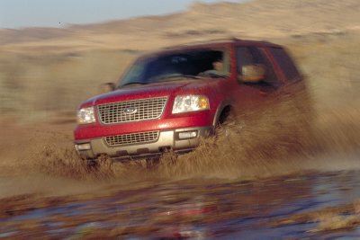 2003 Ford Expedition - A red Ford Expedition navigates through a muddy terrain, creating a splash.