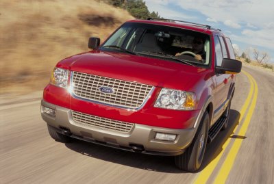 2003 Ford Expedition - A red 2003 Ford Expedition is captured in a 3q-front view as it drives along a paved road.