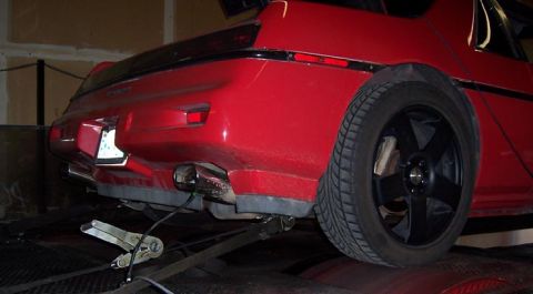 1988 Pontiac Fiero - The rear of a red 1988 Pontiac Fiero is shown on a dynamometer, equipped with aftermarket wheels.