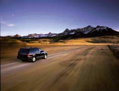 2003 Ford Expedition - 2003 Ford Expedition driving on a dirt road with a mountain range behind it.