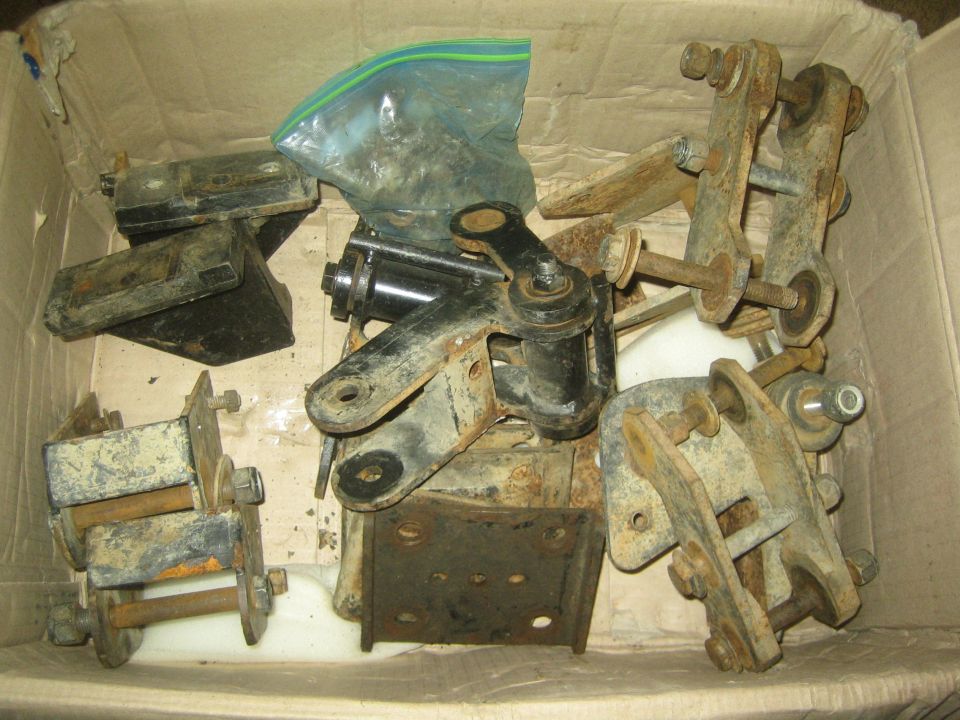 Cardboard box of rusty steel suspension brackets, shackles, and bolts