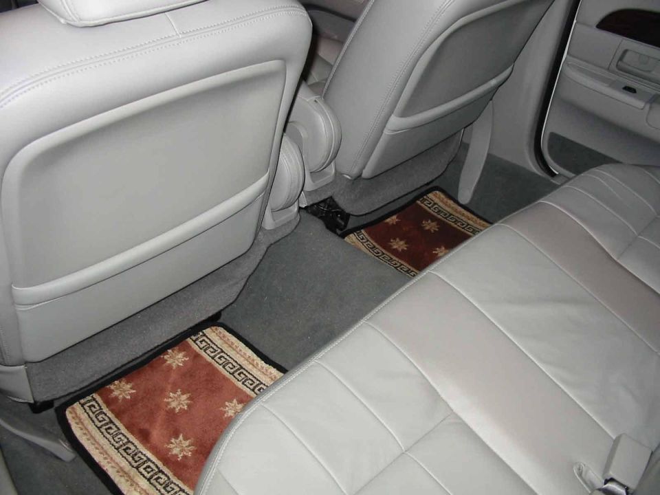 Rear floor of gray leather sedan interior with two patterned burgundy floor mats