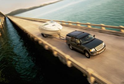 2003 Ford Expedition - A dark SUV tows a boat on a bridge, with water visible on both sides.