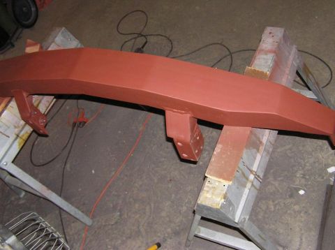 2000 Chevrolet Tahoe - A red-painted metal bumper, likely for a truck or SUV, is shown on sawhorses in a workshop.