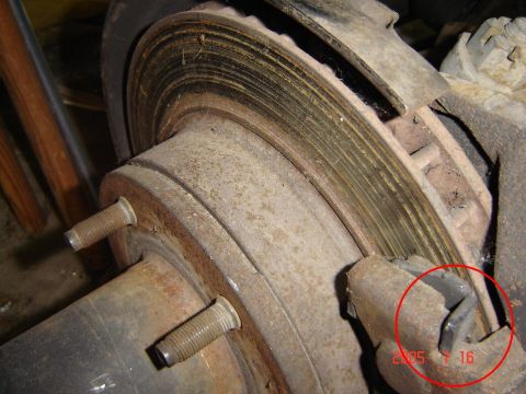 1993 Ford Bronco - Close-up view of a worn brake rotor and caliper assembly, showing signs of rust and wear.