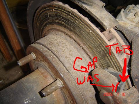 1993 Ford Bronco - This image shows a close-up of a vehicle's brake rotor and caliper assembly, with handwritten annotations indicating a gap and a tab.