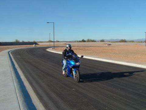2007 Kawasaki Ninja - Rider on a blue sportbike navigates a curved road under a clear blue sky.
