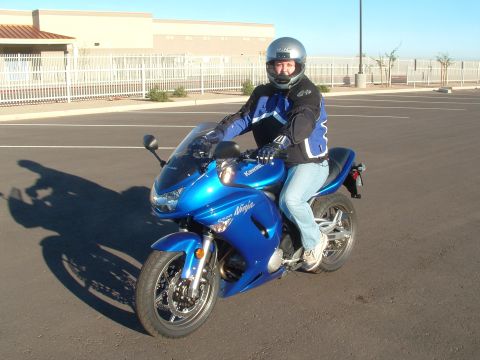 2007 Kawasaki Ninja - A rider on a blue 2007 Kawasaki Ninja motorcycle in a parking lot.