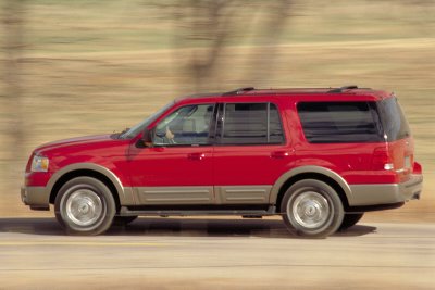 2003 Ford Expedition - A red 2003 Ford Expedition SUV drives down a road, captured in a side profile.
