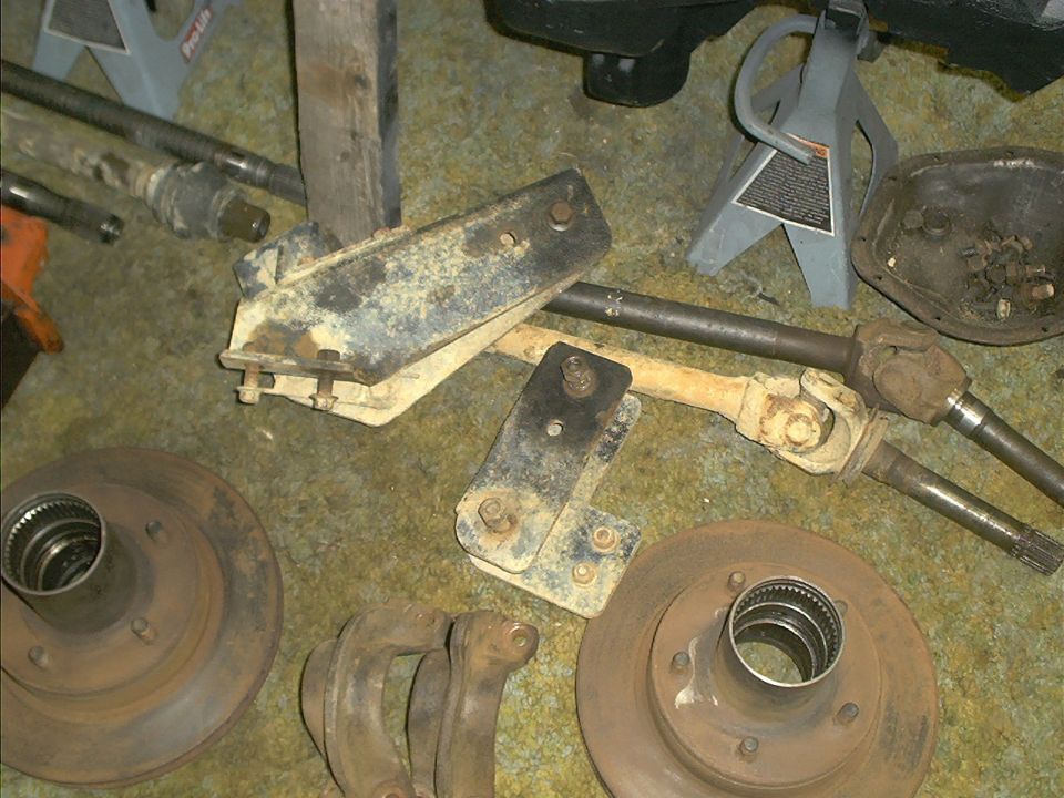 Rusty vehicle suspension parts and brake rotors on carpeted floor