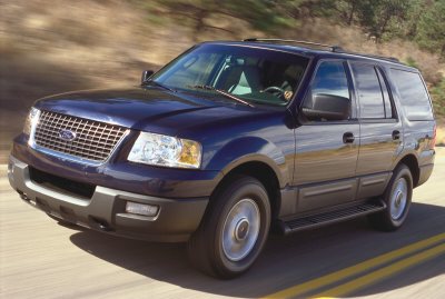 2003 Ford Expedition - Dark blue 2003 Ford Expedition captured in motion on a paved road.