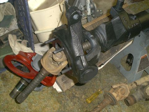 1986 Ford Bronco - Close-up of a vehicle's differential housing and attached U-joint, with tools and other parts in the background.