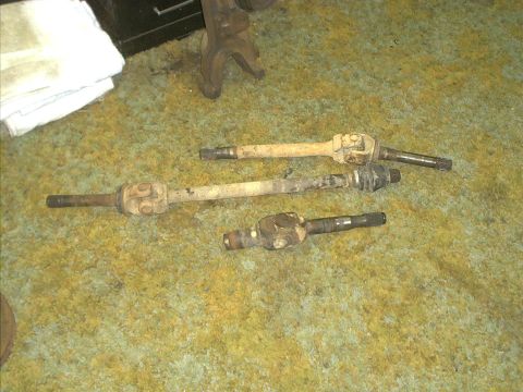 1986 Ford Bronco - Several driveshafts are laid out on a green carpet, possibly for repair or replacement.
