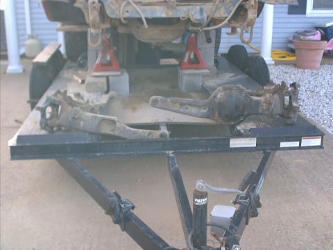 1986 Ford Bronco - A trailer carries the frame and suspension components of a vehicle undergoing repair or disassembly.