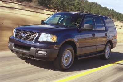 2003 Ford Expedition - A dark blue Ford Expedition is captured in a three-quarter front view while driving on a paved road.